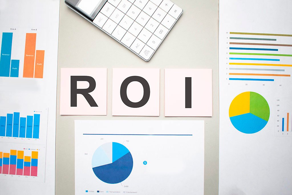 C&aacute;lculo do ROI : Papeis com gr&aacute;ficos coloridos, calculadora e a palavra ROI em uma superficie