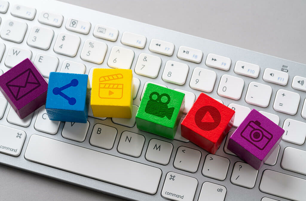 Teclado de computdor branco com vários quadradinhos coloridos e de madeira com ícones de conteúdo digital