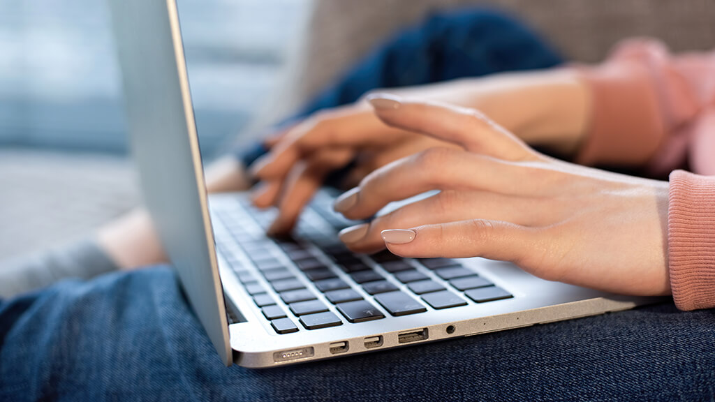 O que &eacute; criador de conte&uacute;do digital? : criadora de conte&uacute;do com laptop no colo trabalhando