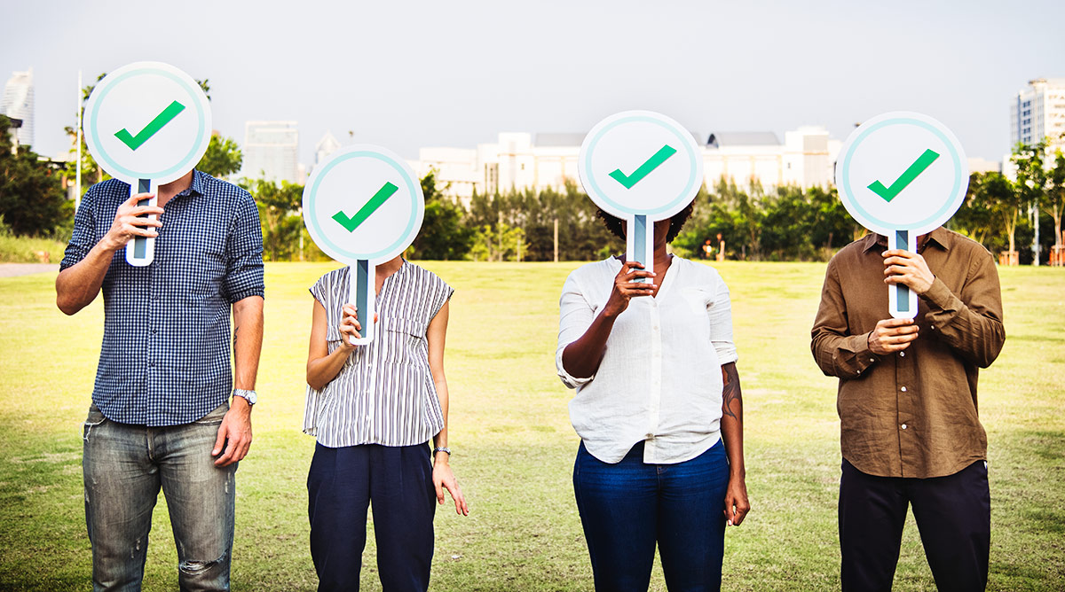 Quatro pessoas com a cara tampada por uma placa redonda, contendo s&iacute;mbolo de verificado, representando como encontrar os influenciadores certos e entrar em contato. Fonte: &copy;Freepik 