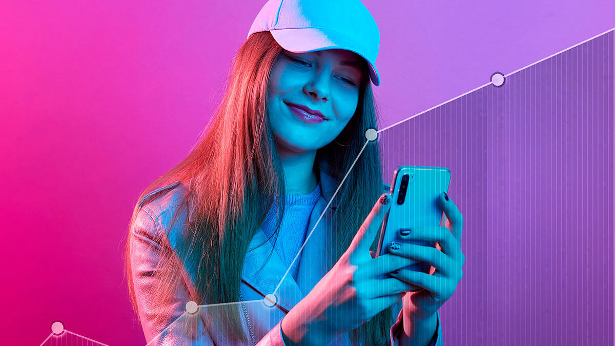 Foto rosada de uma influencer de boné com um celular nas mãos e em sua frente um gráfico em sentido de crescimento, representando as tendências para o marketing de influência em 2023. Foto: @Freepik
