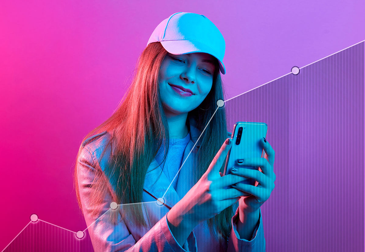 Foto rosada de uma influencer de boné com um celular nas mãos e em sua frente um gráfico em sentido de crescimento, representando as tendências para o marketing de influência em 2023. Foto: @Freepik