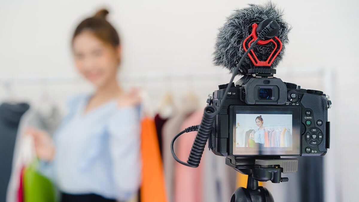 Influencer segurando sacolas coloridas fazendo divulgação em live