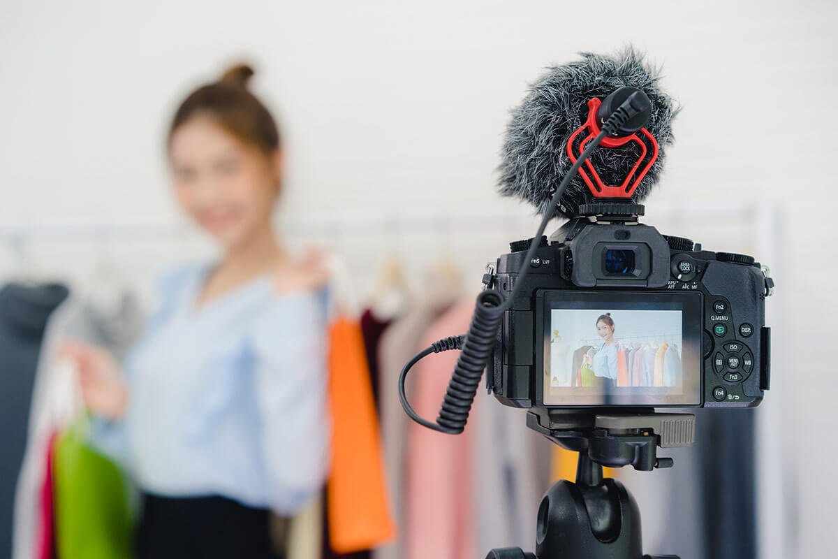 Influencer segurando sacolas coloridas fazendo divulgação em live