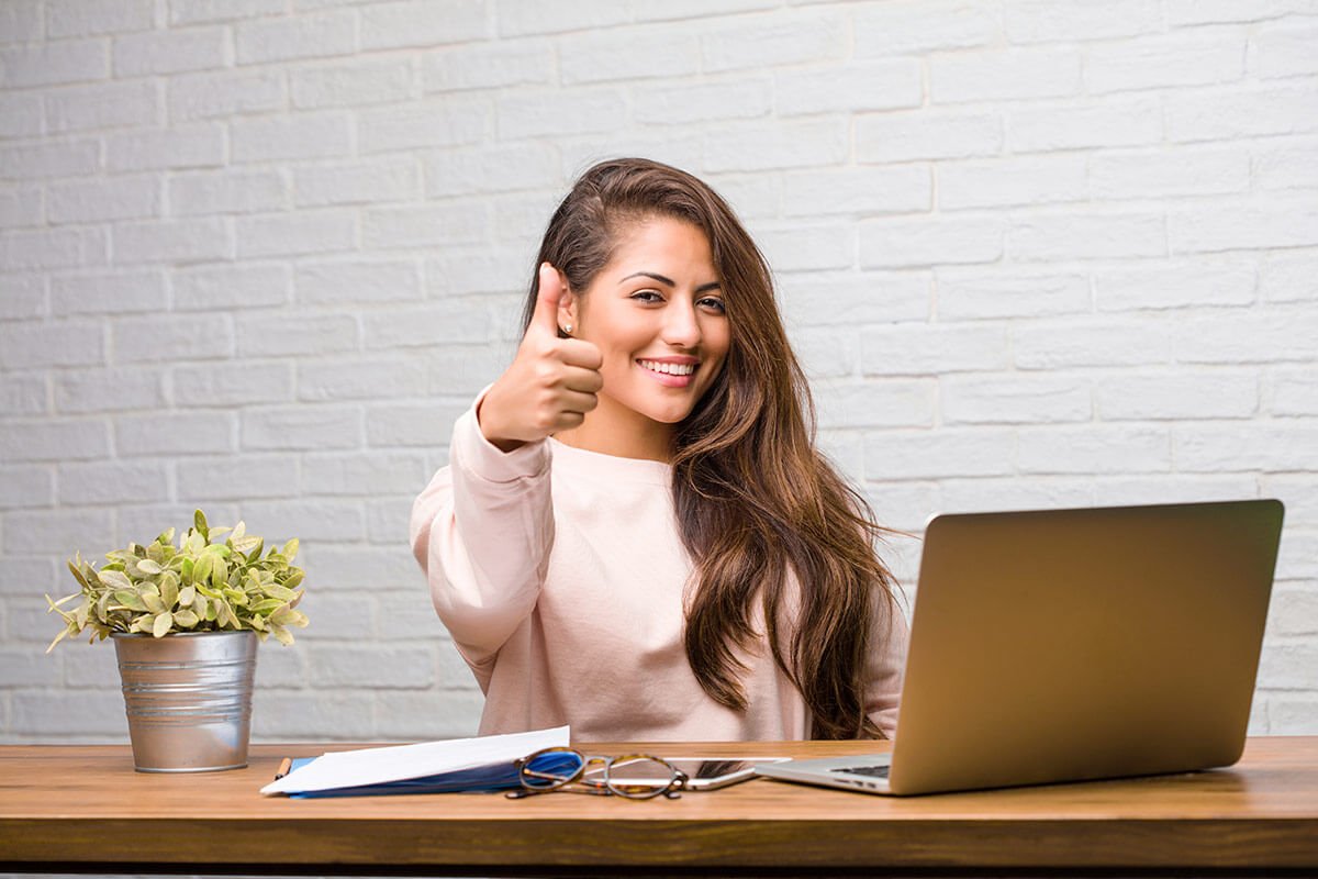Influencer em frente a um notebook fazendo sinal de "positivo", demonstrando que influenciador digital pode ser MEI. Foto: @Freepik