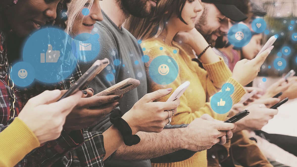 Grupo de pessoas, uma ao lado da outra, utilizando as redes sociais