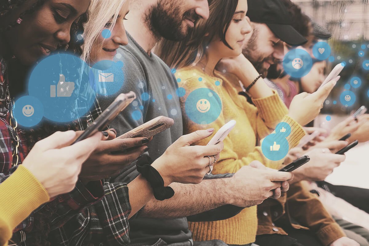 Grupo de pessoas, uma ao lado da outra, utilizando as redes sociais