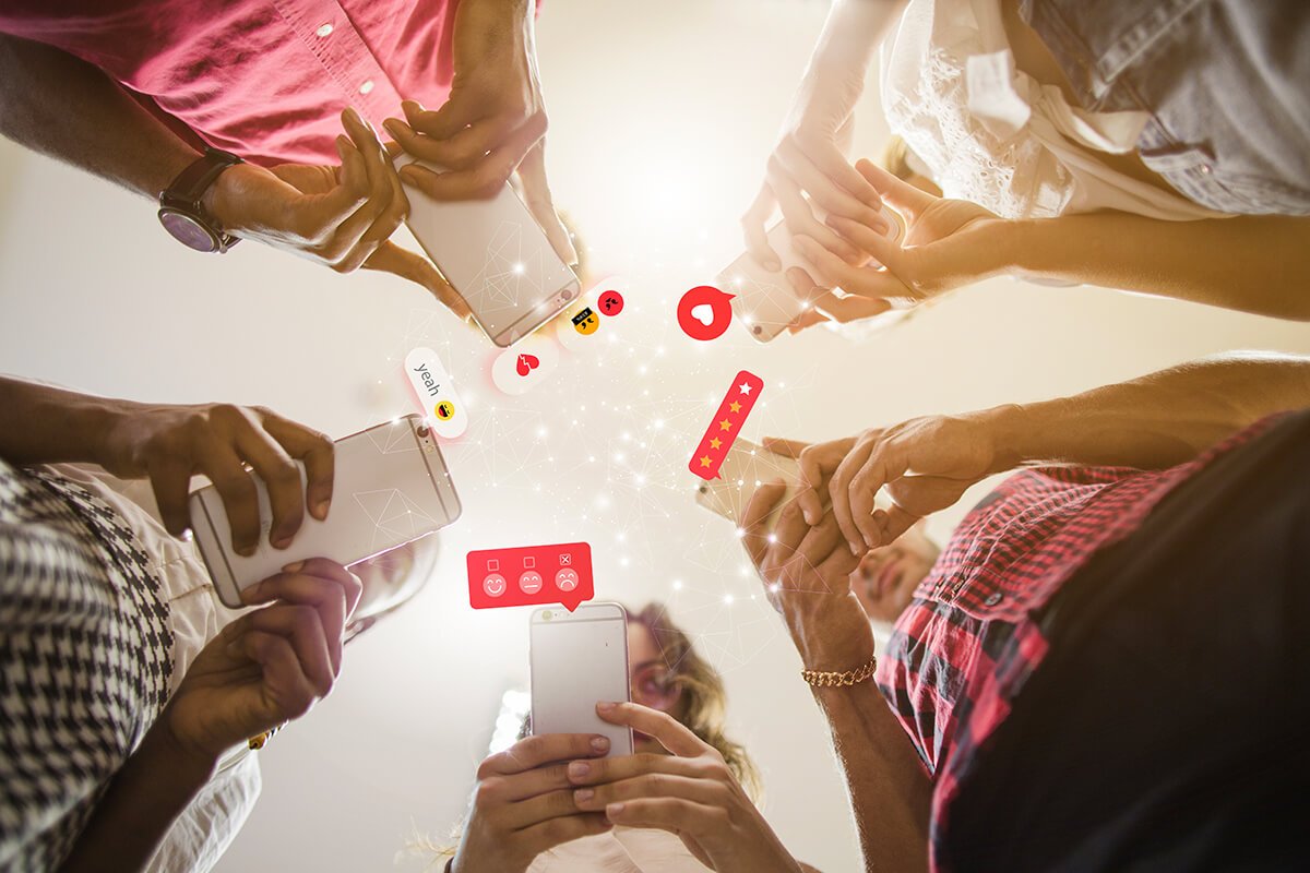 Cinco colaboradores est&atilde;o em p&eacute;, formando um c&iacute;rculo, enquanto utilizam seus celulares para praticarem suas habilidades de influ&ecirc;ncia. Fonte: @Freepik